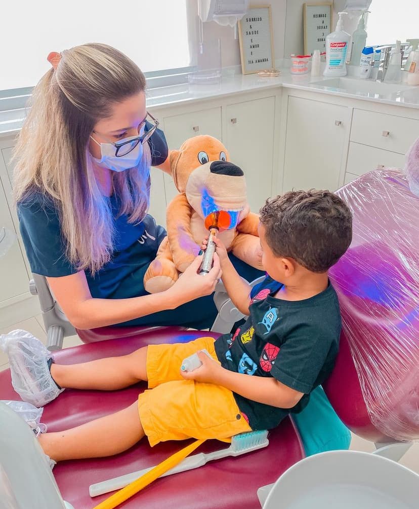 Dentista demonstrando cuidados bucais com pelúcia para criança
