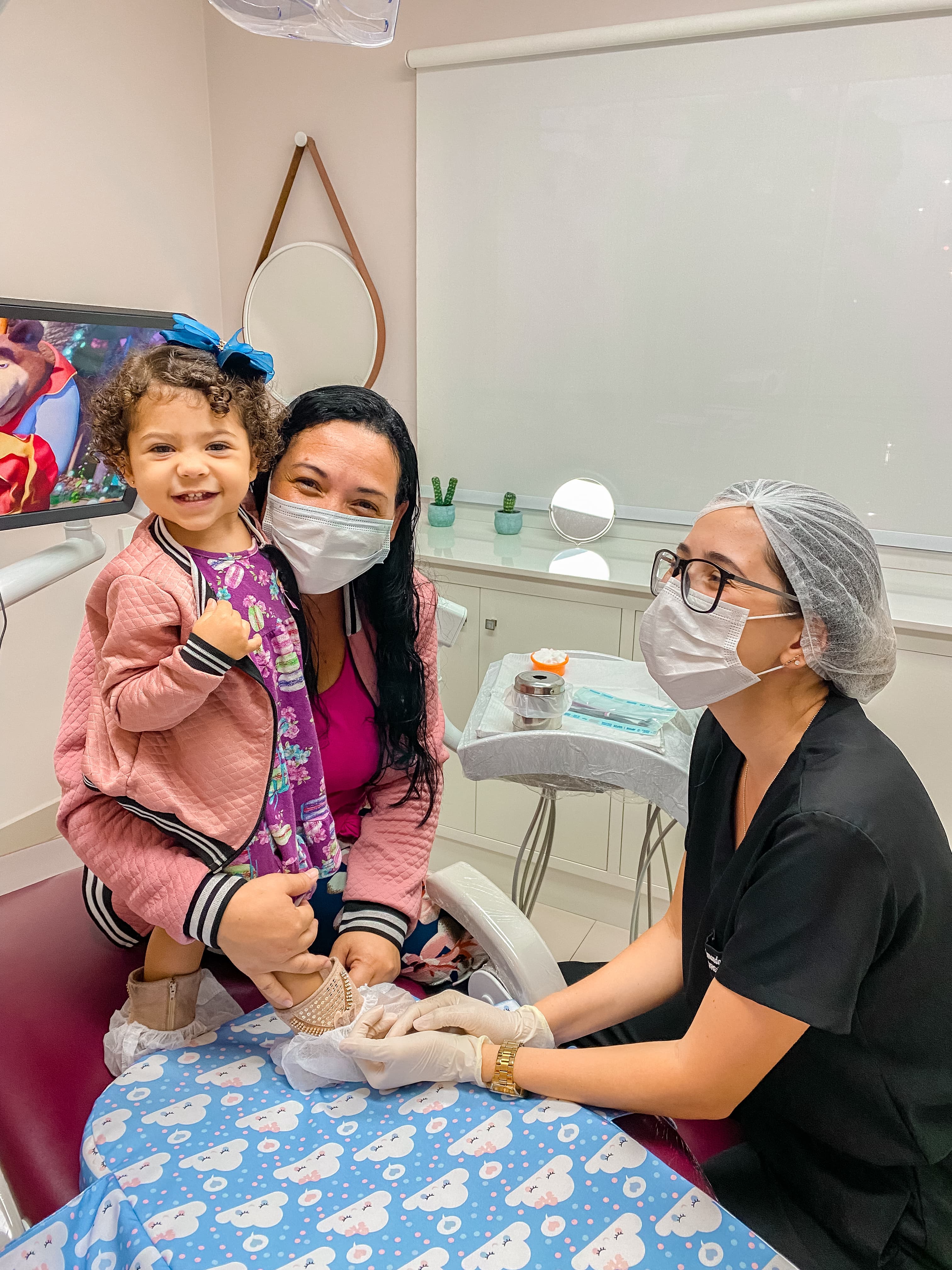 Bebê sorridente com mãe e profissional da clínica